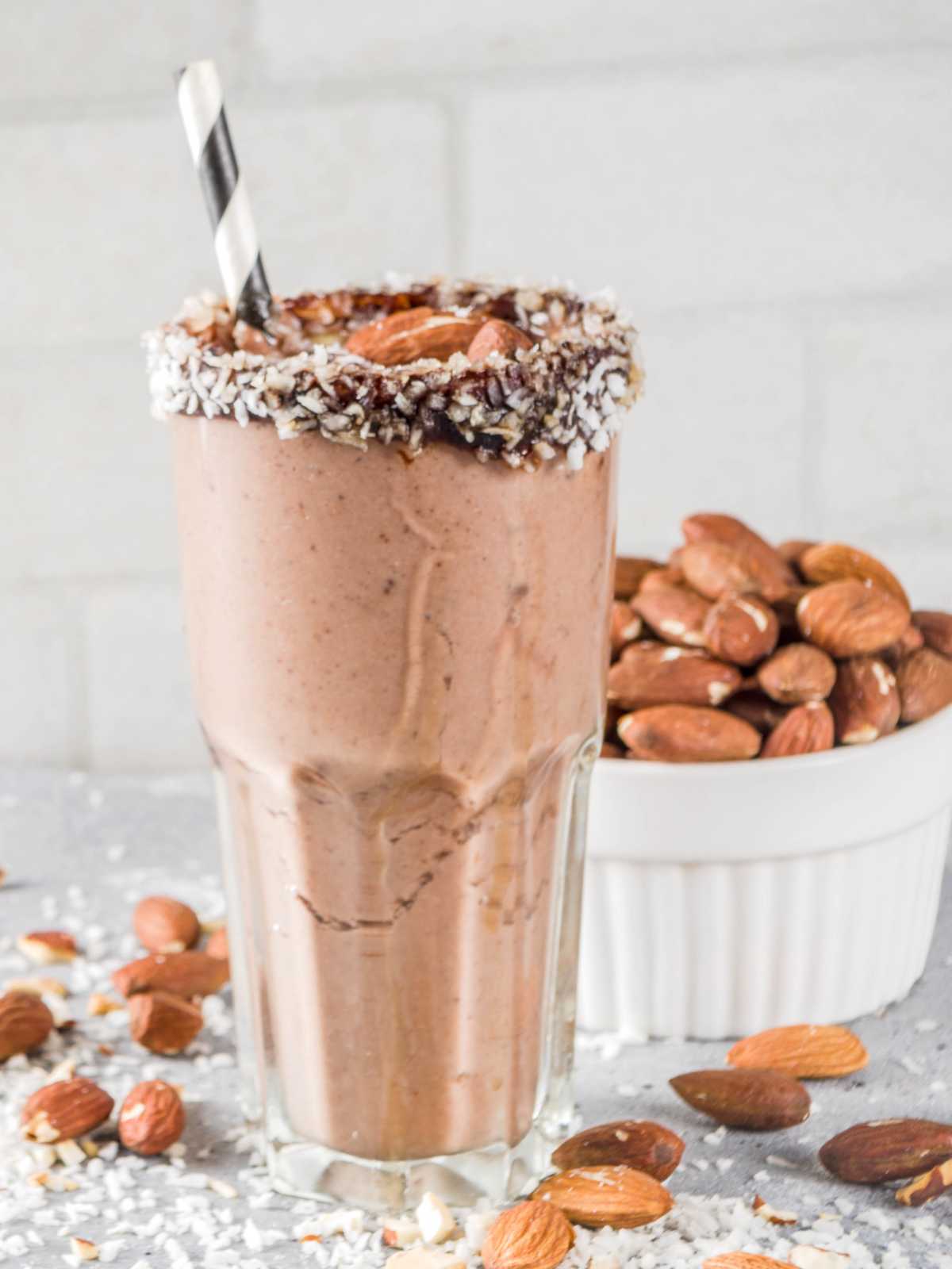 Almond joy smoothie in a glass with coconut chocolate dipped rim.