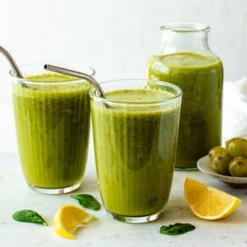 Two glasses filled with green tea smoothie, next to a glass jar with extra smoothie.