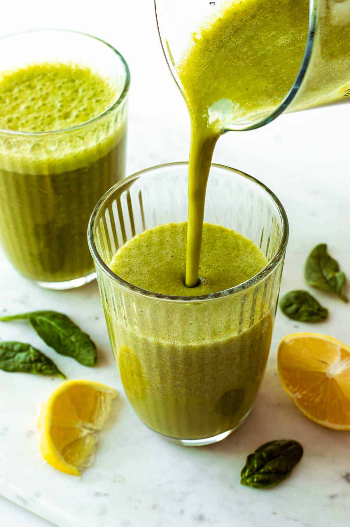 A pitcher pouring the green tea smoothie into a glass.