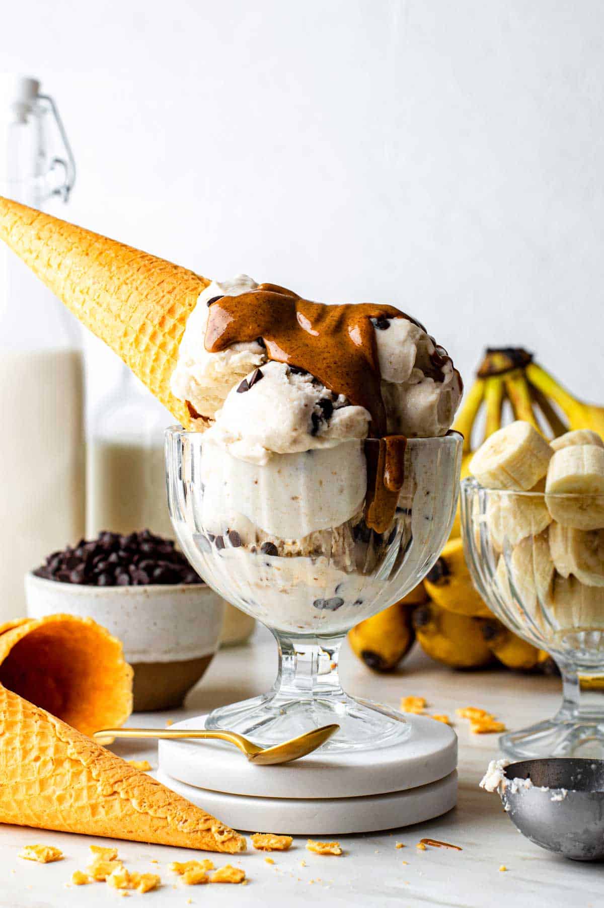 Scoops of banana nice cream mixed with chocolate chips in a bowl with a drizzle of peanut butter on top.