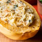 Spaghetti squash half topped with creamy sauces and herbs.