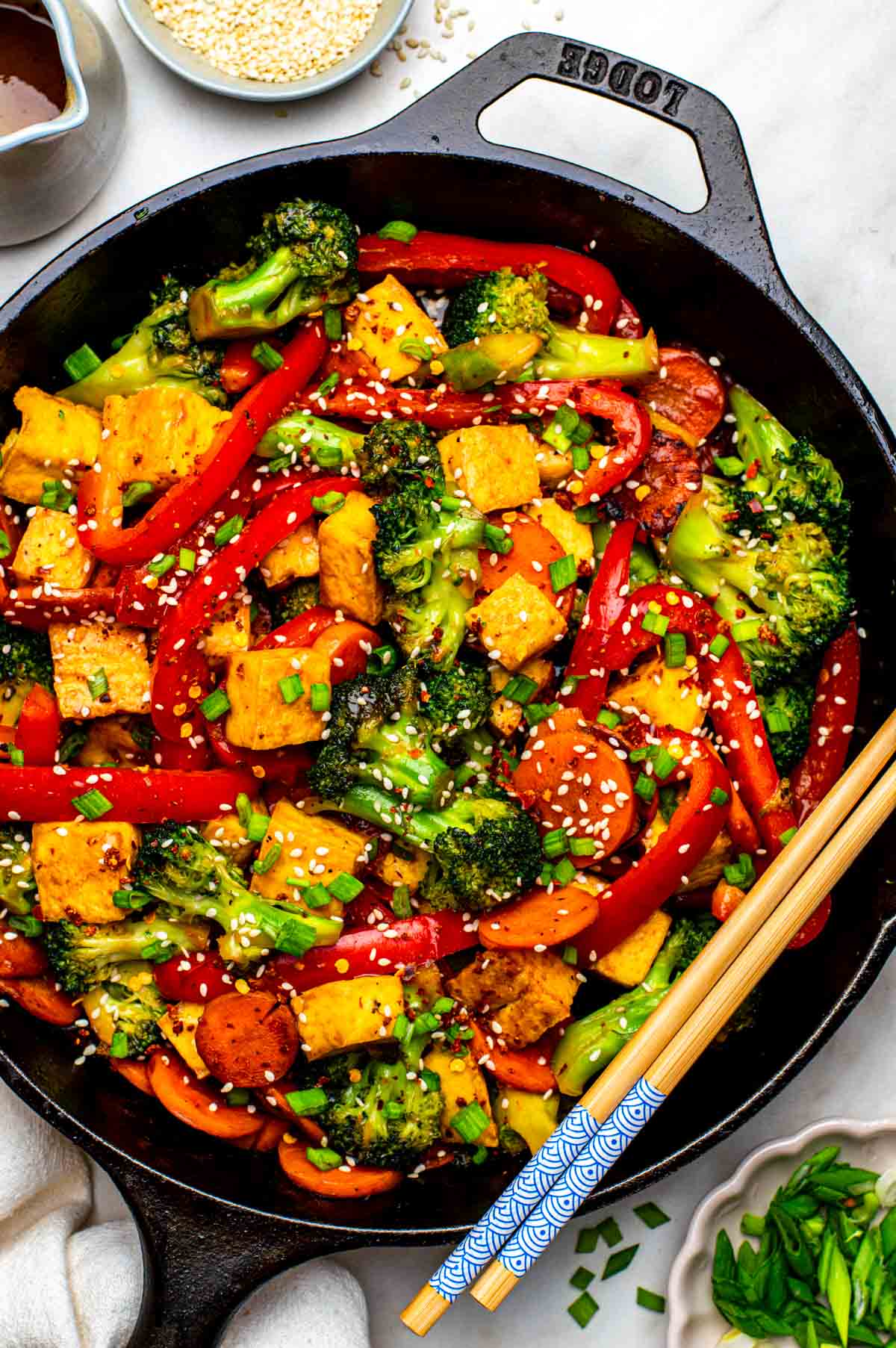 Vegan stir fry in a skillet topped with sesame seeds.