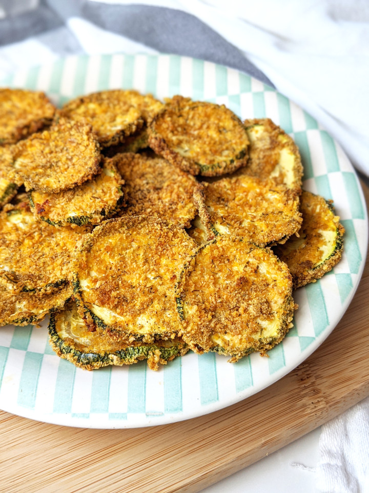 These Vegan Baked Zucchini chips are oven-baked, crispy, and irresistible! They're a delicious and healthy alternative to regular chips and are incredibly easy to make! #vegansnack #veganchips #healthysnack #easysnack #bakedchips #zucchinichips