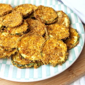 These Vegan Baked Zucchini chips are oven-baked, crispy, and irresistible! They're a delicious and healthy alternative to regular chips and are incredibly easy to make! #vegansnack #veganchips #healthysnack #easysnack #bakedchips #zucchinichips