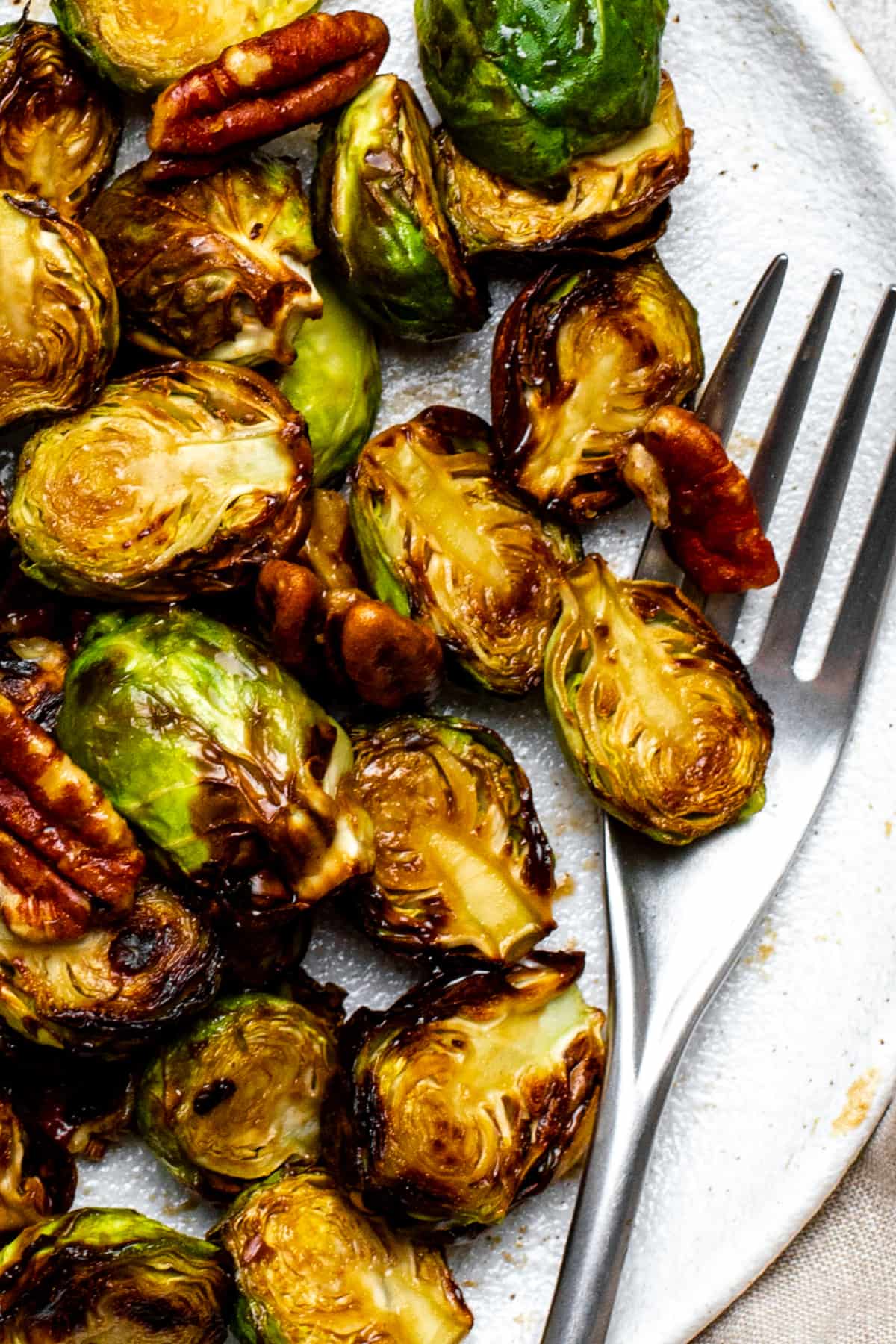 A plate of roasted maple balsamic brussels sprouts with a fork.