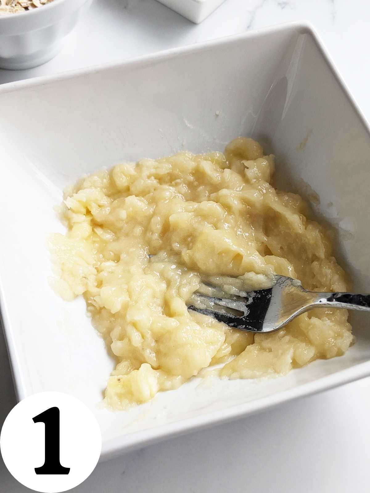 Banana mashed with a fork in a bowl.
