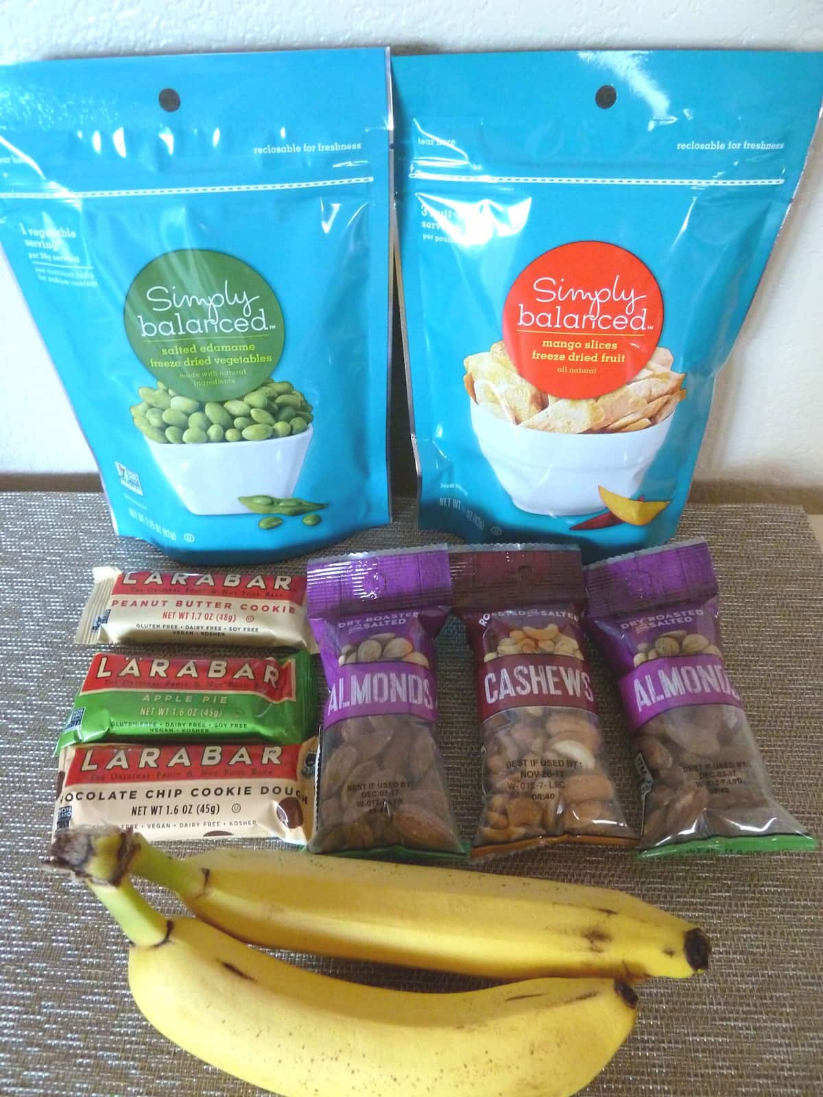 Vegan travel snacks including freeze dried fruit, snack bars, roasted nuts, and bananas.