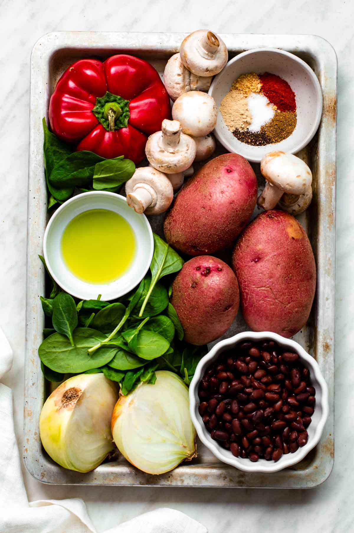 Gathered ingredients for this vegetable hash on a baking tray.