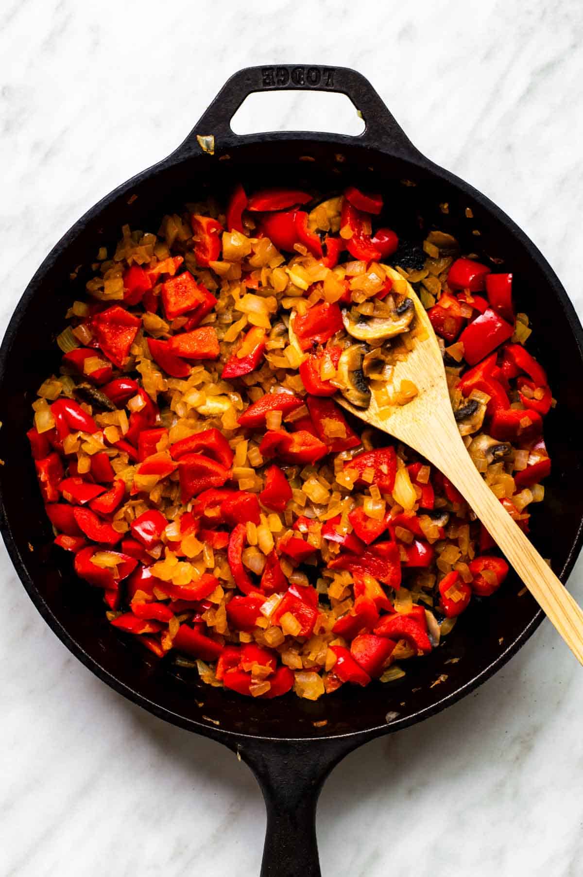 A skillet of sauteed onion, mushrooms, and bell pepper.