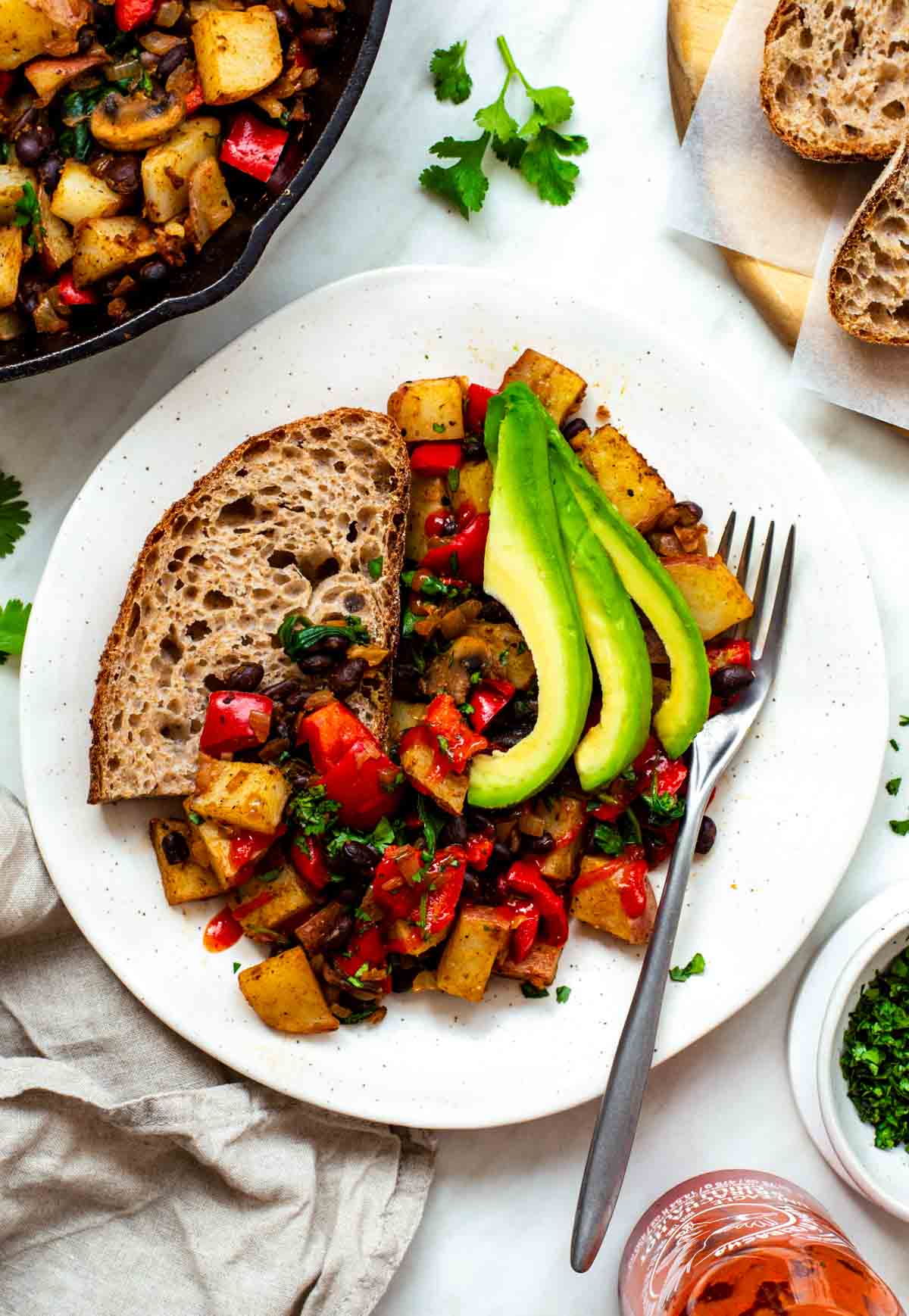 Veggie hash served on a placed with a slice of toast and avocado.