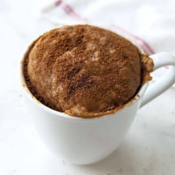 Snickerdoodle mug cake after microwaving, topped with cinnamon sugar.