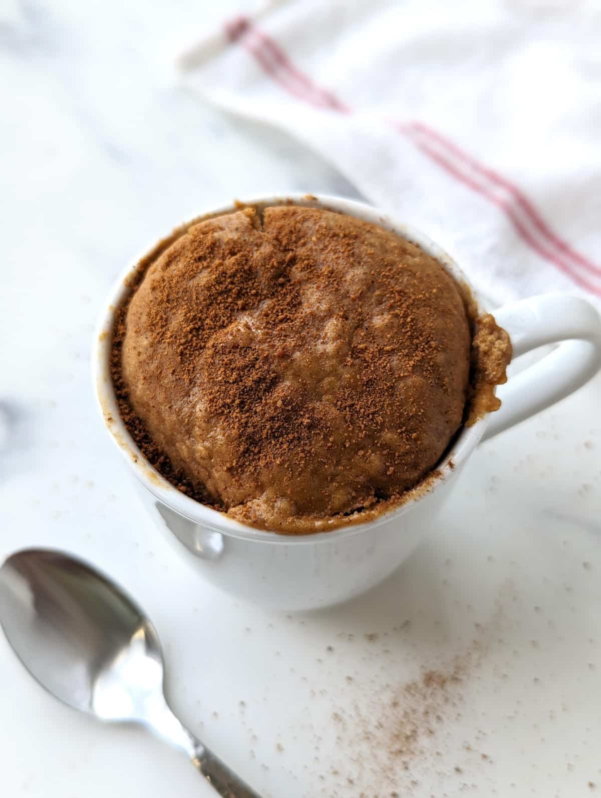 Baked snickerdoodle mug cake after microwaving, topped with cinnamon sugar.