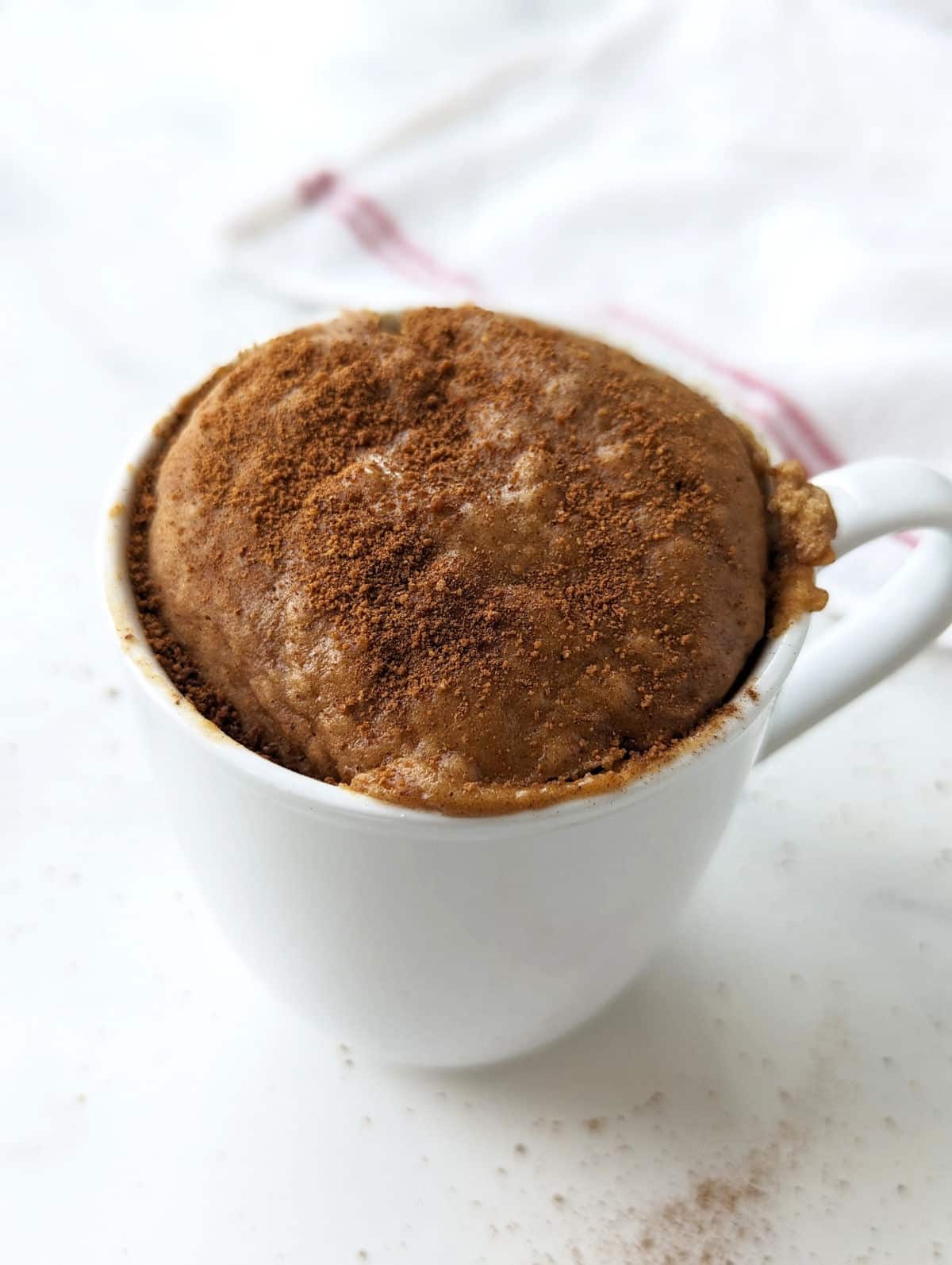 Snickerdoodle mug cake after microwaving, topped with cinnamon sugar.