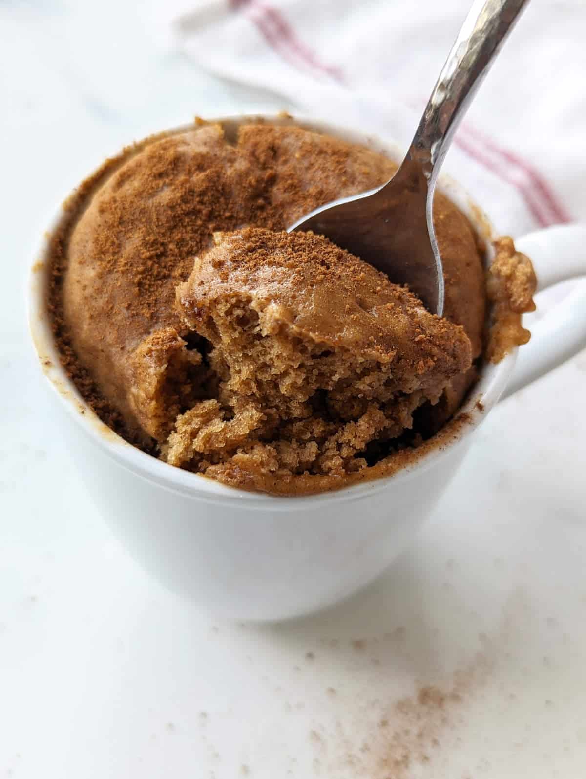 A spoon digging into the snickerdoodle mug cake, showing the fluffy interior.