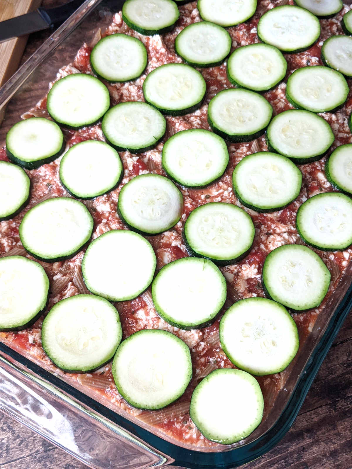 Tofu pasta mixture in casserole dish topped with sliced zucchini.