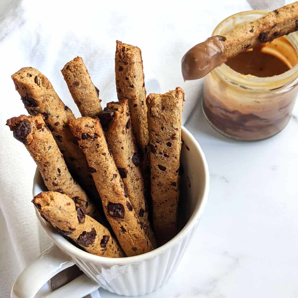 Cookie fries in a mug with chocolate dip served in a small jar next to it.