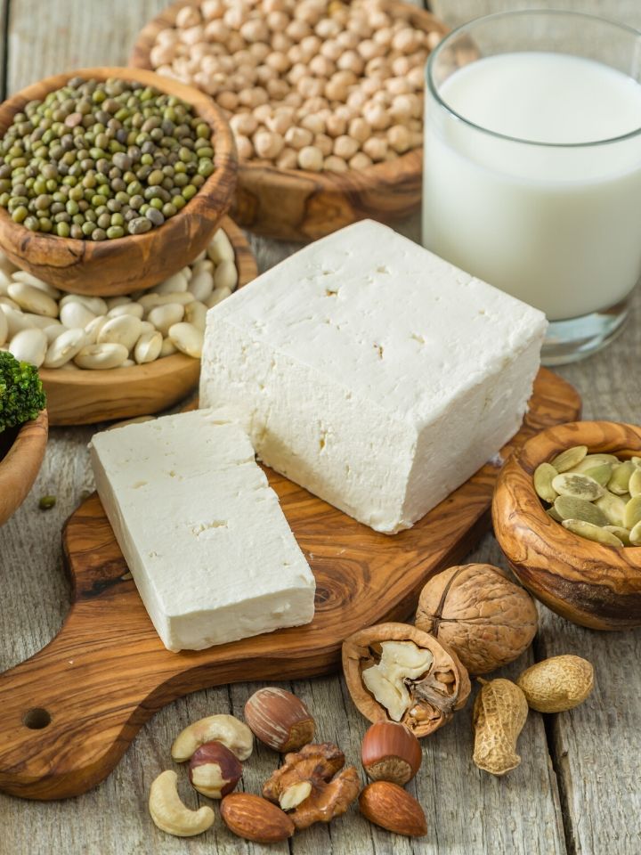 A variety a vegan protein substitutes scattered around such as tofu, soy milk, chickpeas, peas, and nuts.