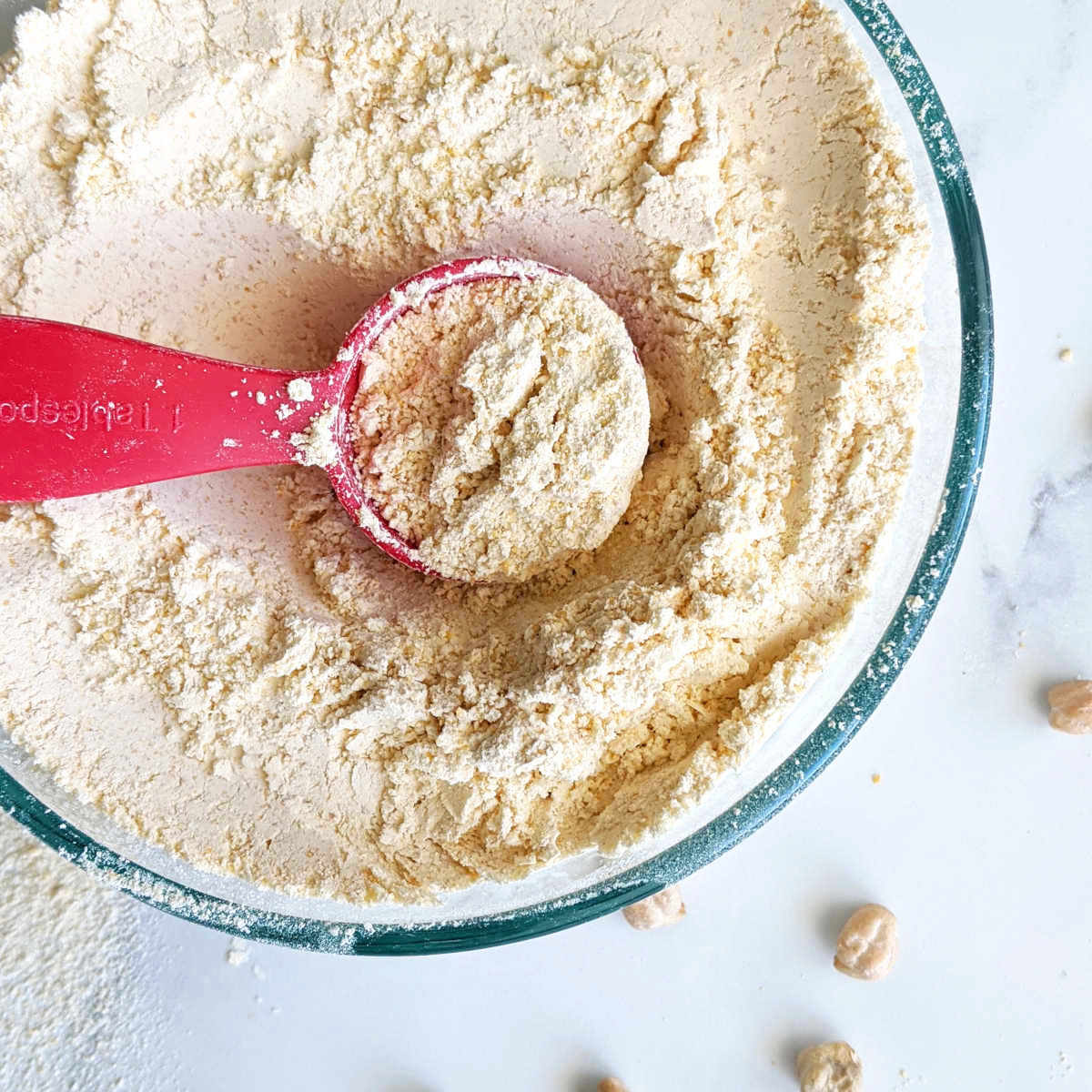 Homemade chickpea flour in a bowl with a tablespoon.