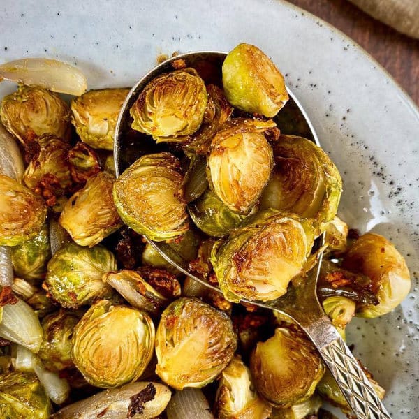 roasted brussels sprouts in a bowl with a large serving spoon