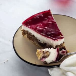 A slice of cheesecake with a fork holding a bite of it