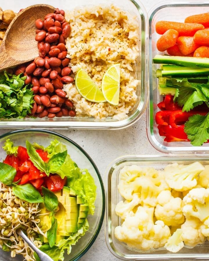 Several meal prep containers full of colorful vegan food