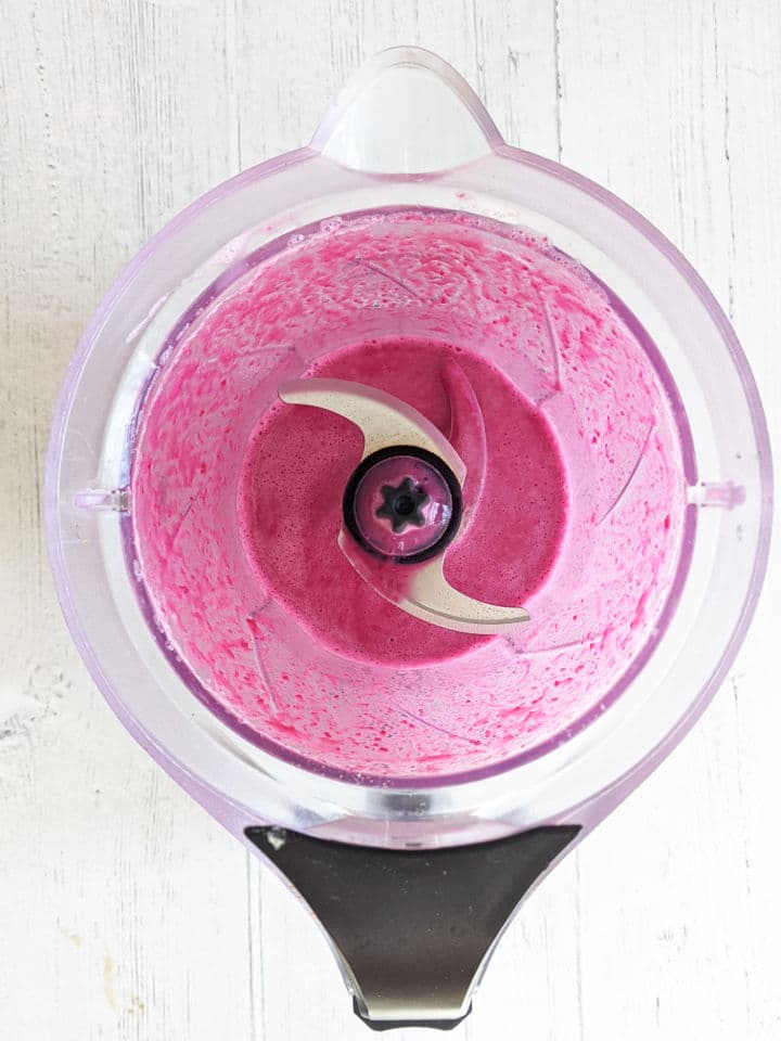 A blender with beets blended into milk