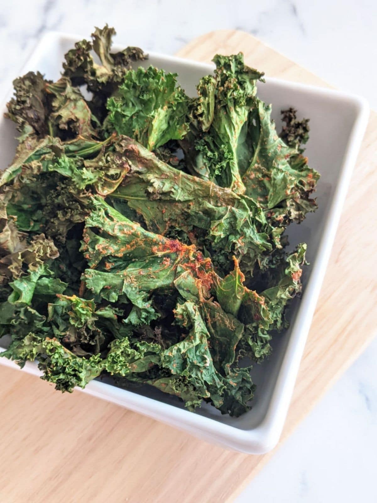 Kale chips in a bowl on a cutting board