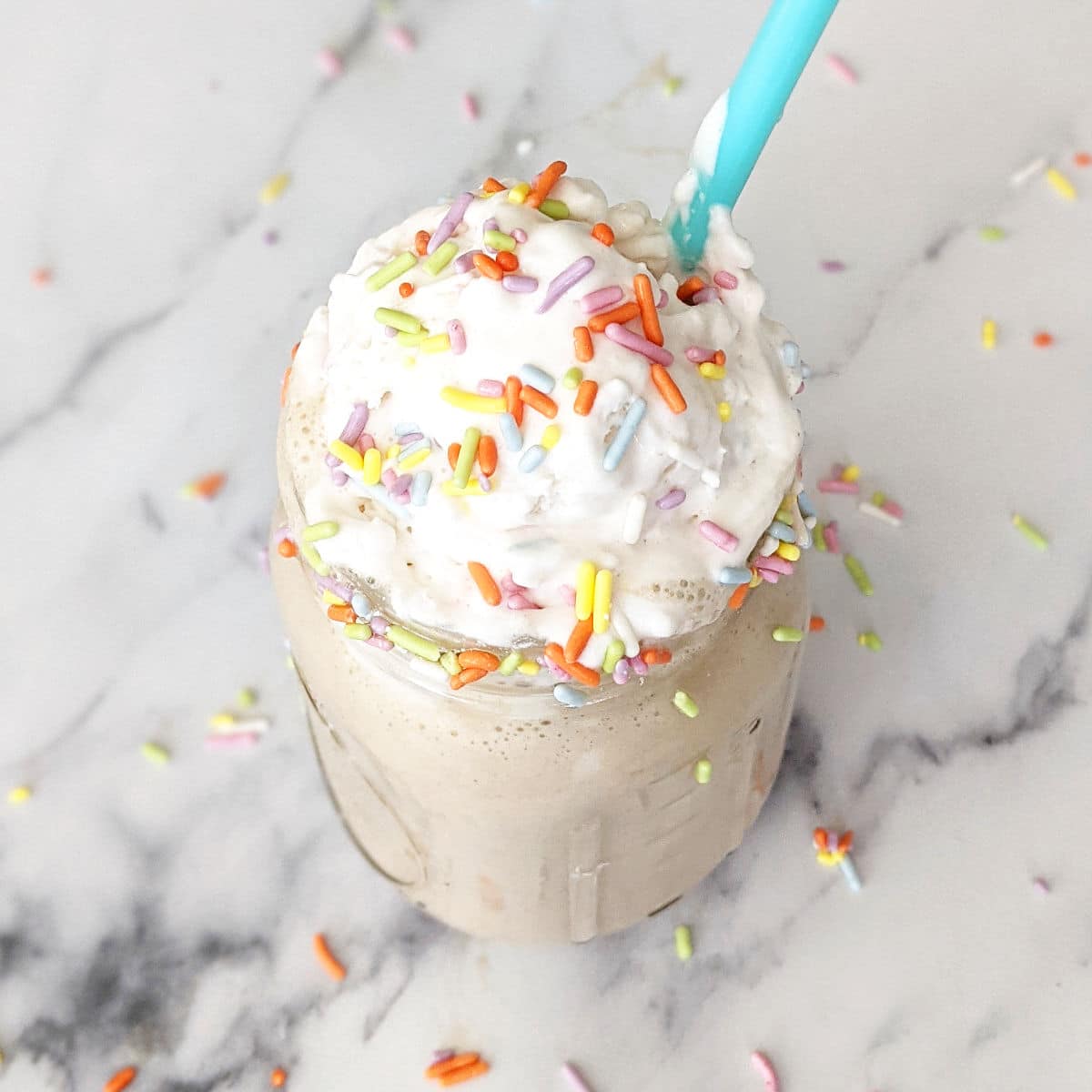 Birthday cake shake topped with coconut whipped cream and sprinkles
