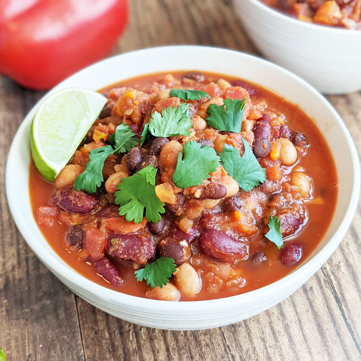 Bowl of finished chili topped with cilantro and a lime wedge.