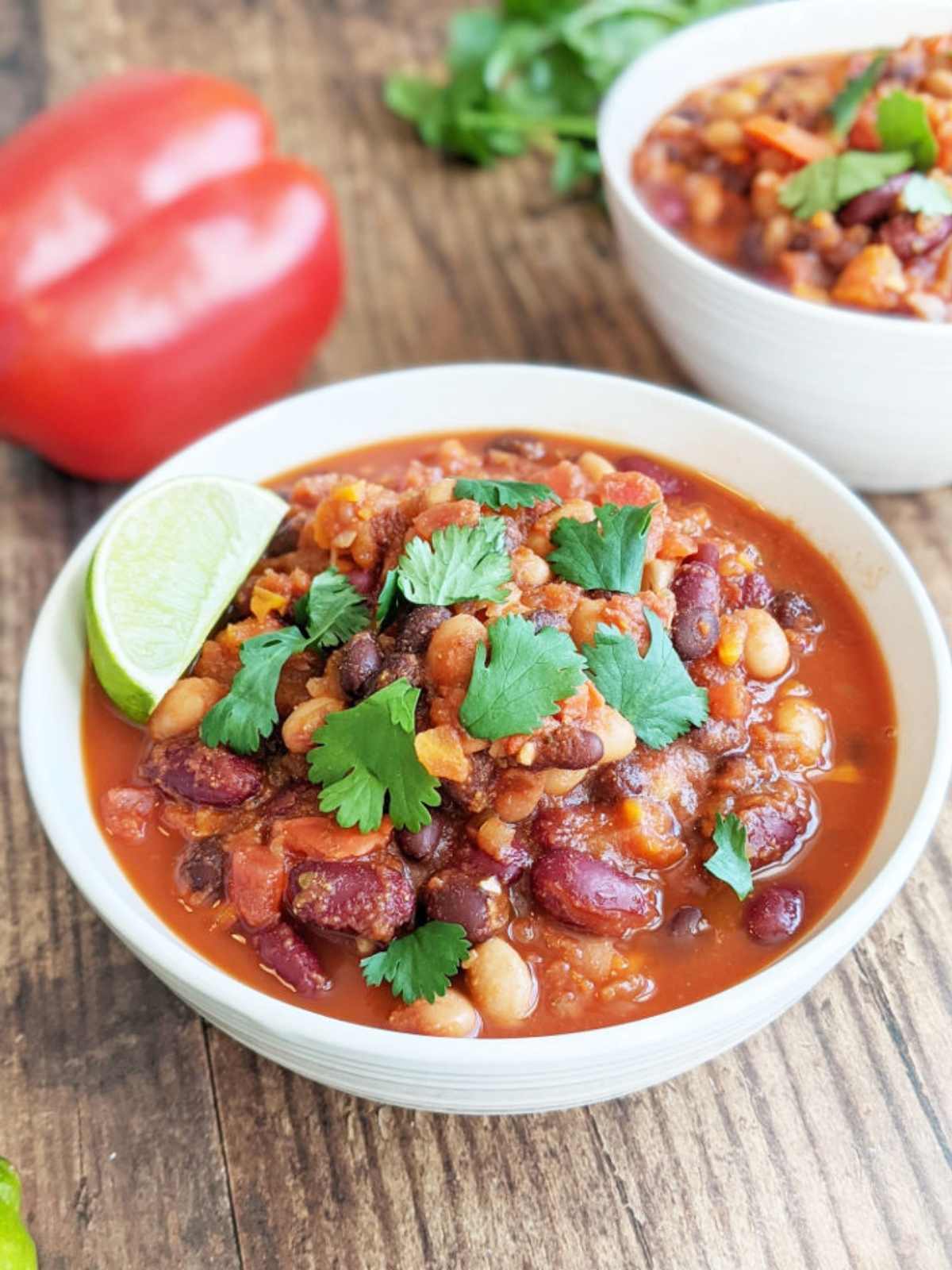 Bowl of finished chili topped with cilantro and a lime wedge.