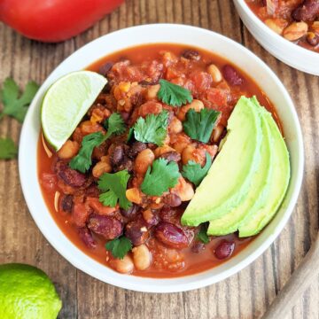 Bowl of finished chili topped with avocado, cilantro, and a lime wedge