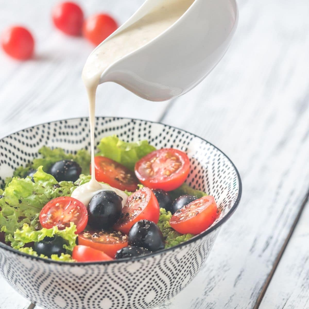 creamy dressing pouring over a salad in a bowl