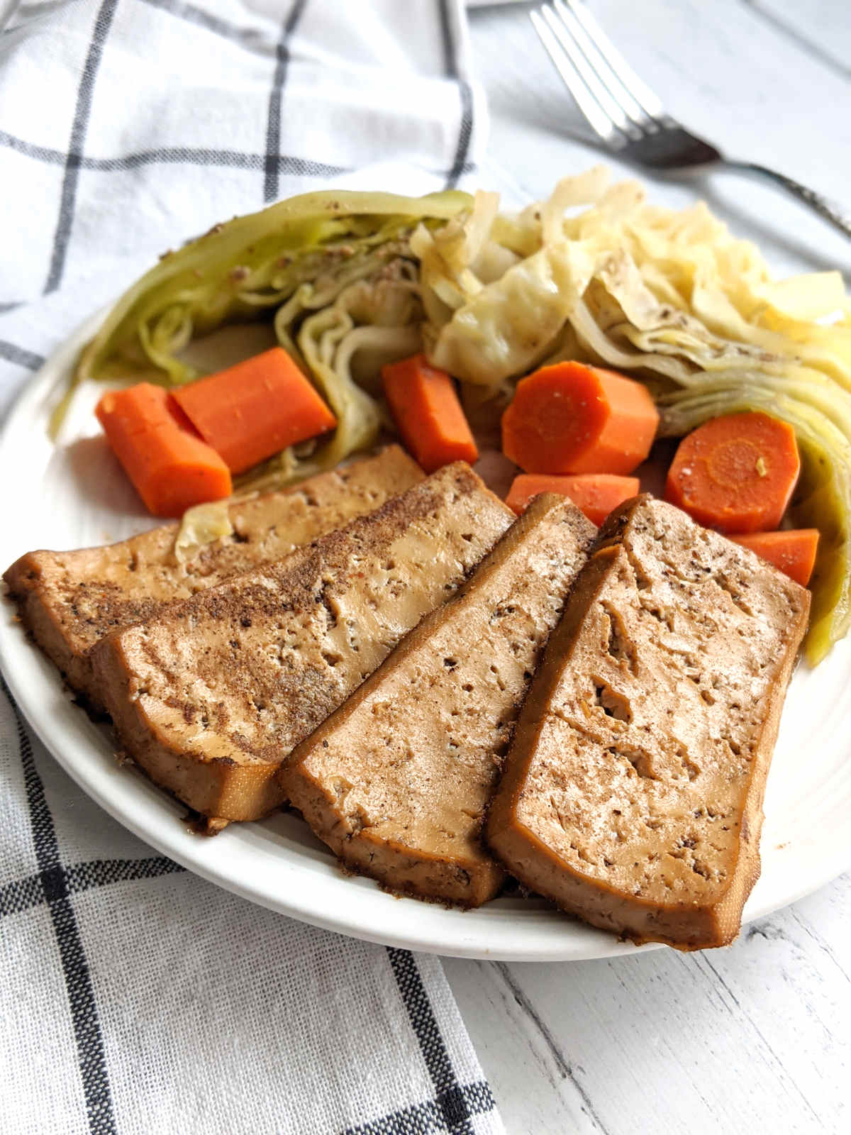 Vegan corned beef with braised cabbage and carrots on a plate.