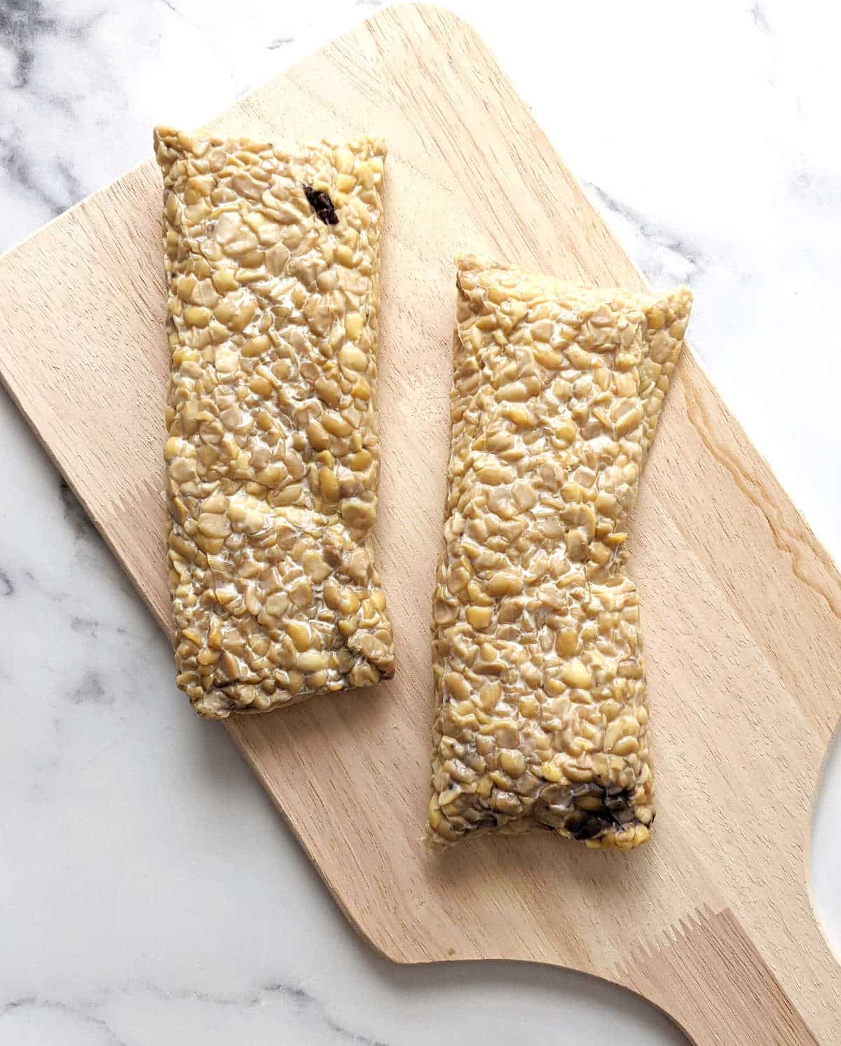 Two blocks of tempeh on a cutting board