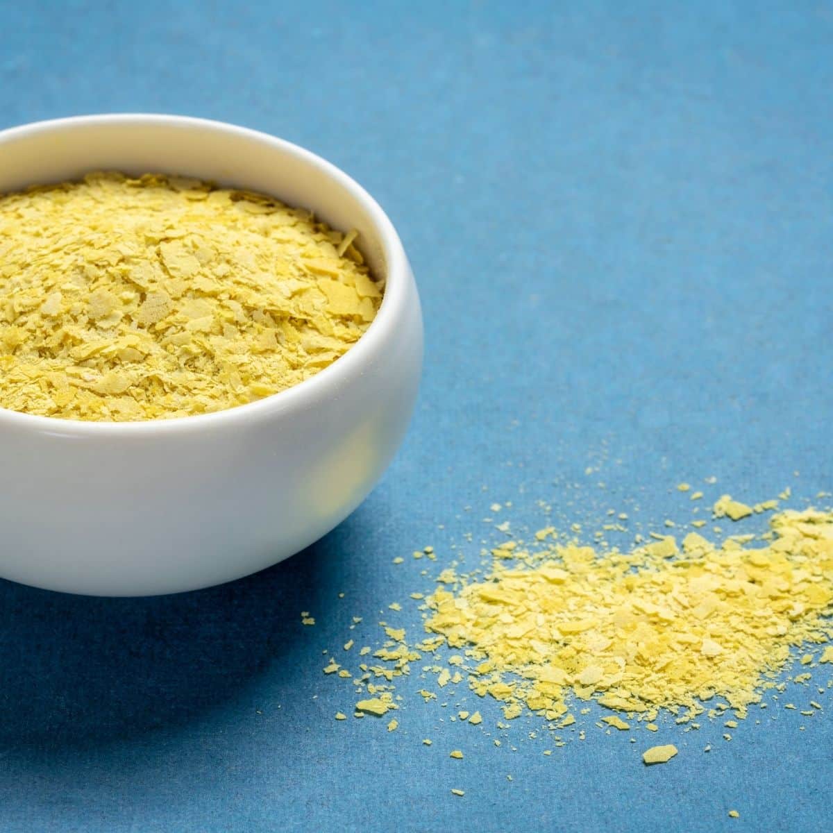 Nutritional yeast in a bowl with some spilt next to it