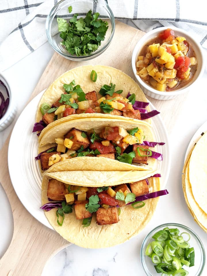 Over head shot of finished tofu tacos on a plate surrounded by additional toppings