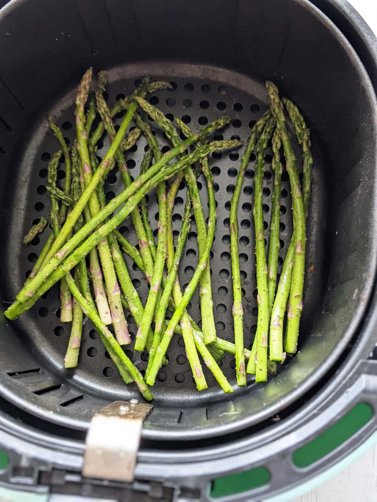 Seasoned asparagus in an air fryer basket