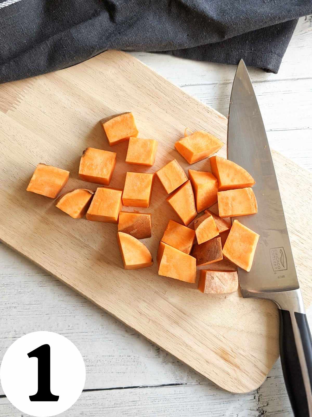 Sweet potato sliced into cubes on a cutting board.