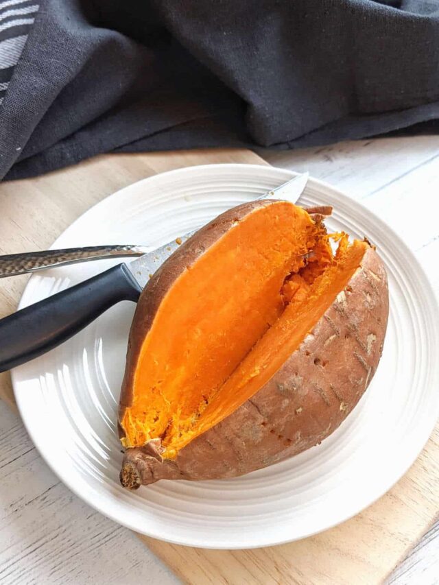 Whole sweet potato sliced in half on plate.