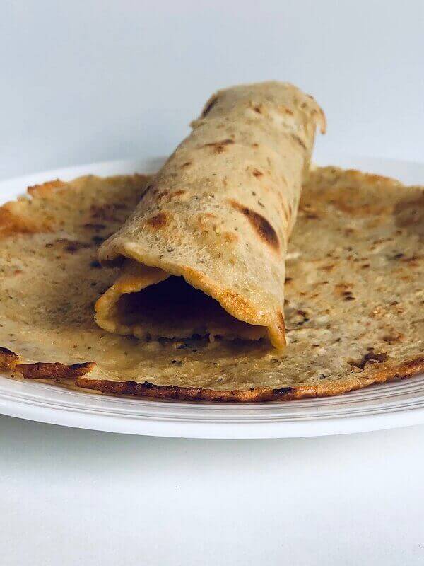 Chickpea flour tortilla wrapped up on a plate.