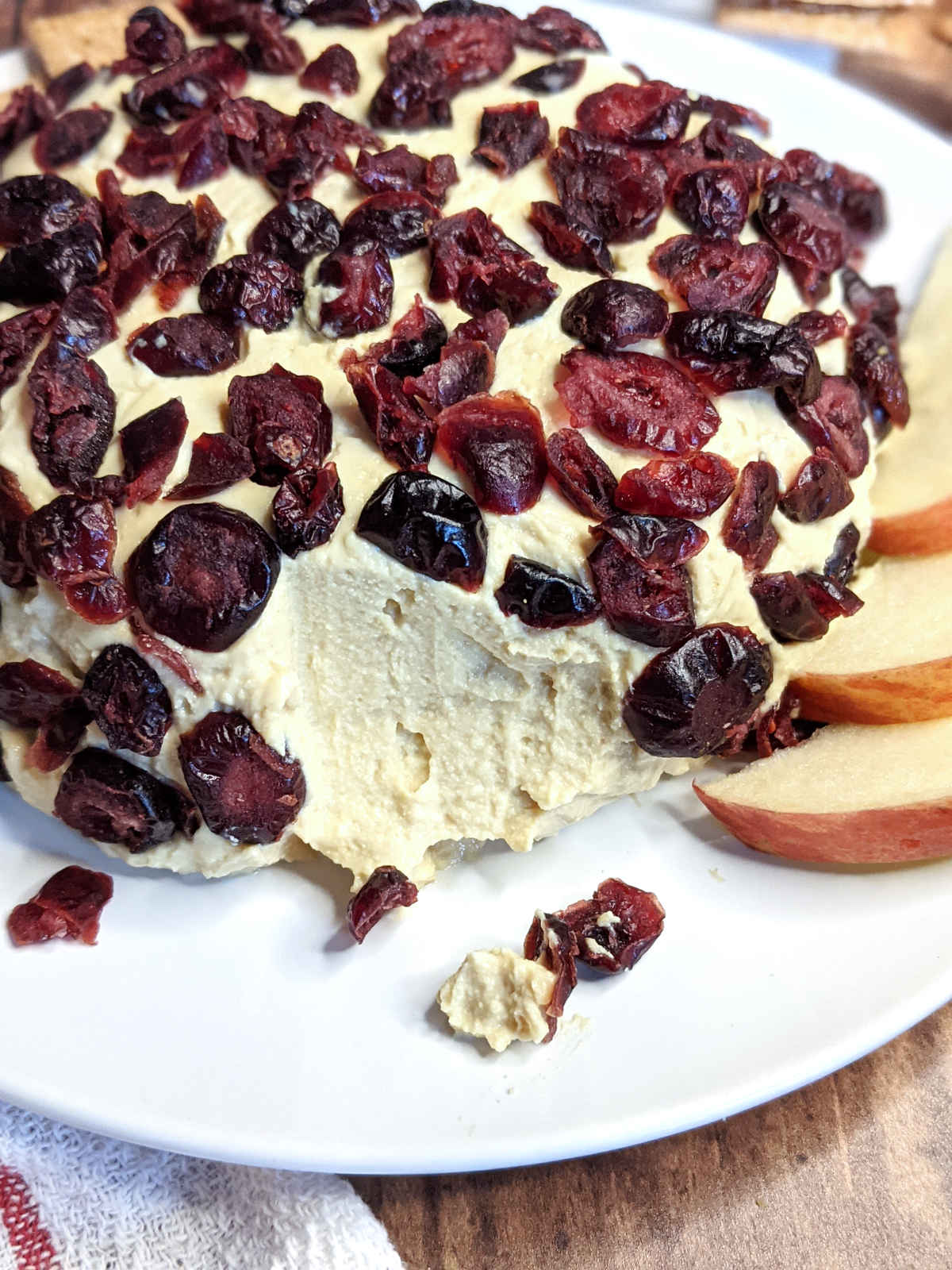 Cranberry vegan cheese ball on platter with crackers and sliced apples.