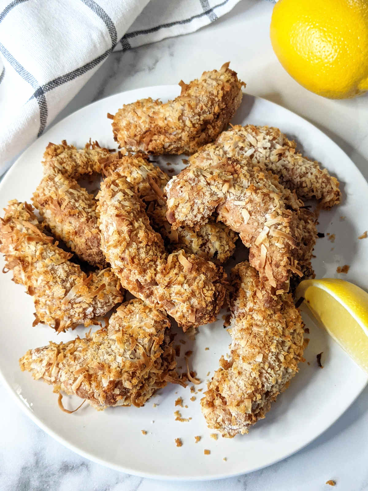 Coconut crusted vegan shrimp on a plate with lemon wedge.