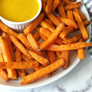 Sweet potato fries on serving plate with small bowl of honey mustard.