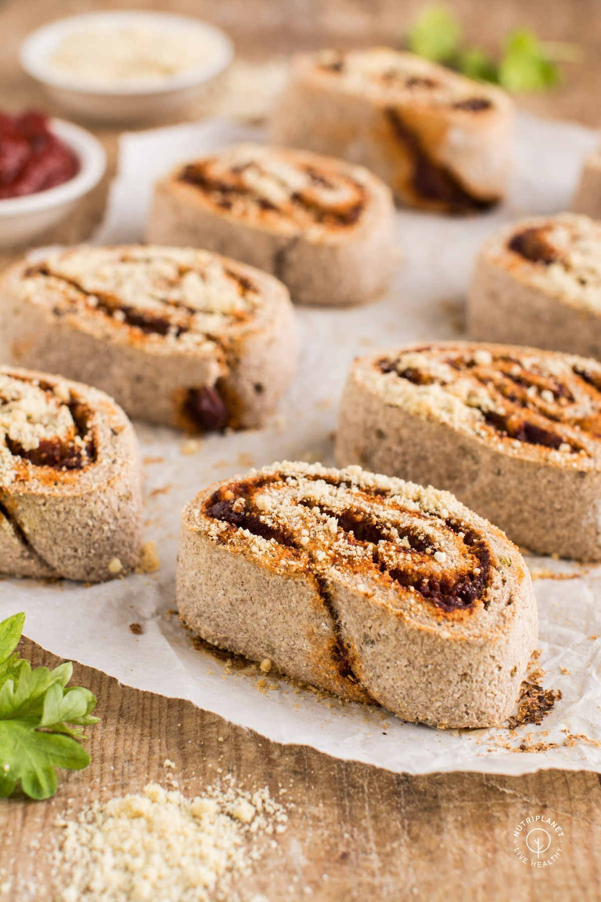 Pizza rolls on parchment paper sprinkled with vegan parmesan.