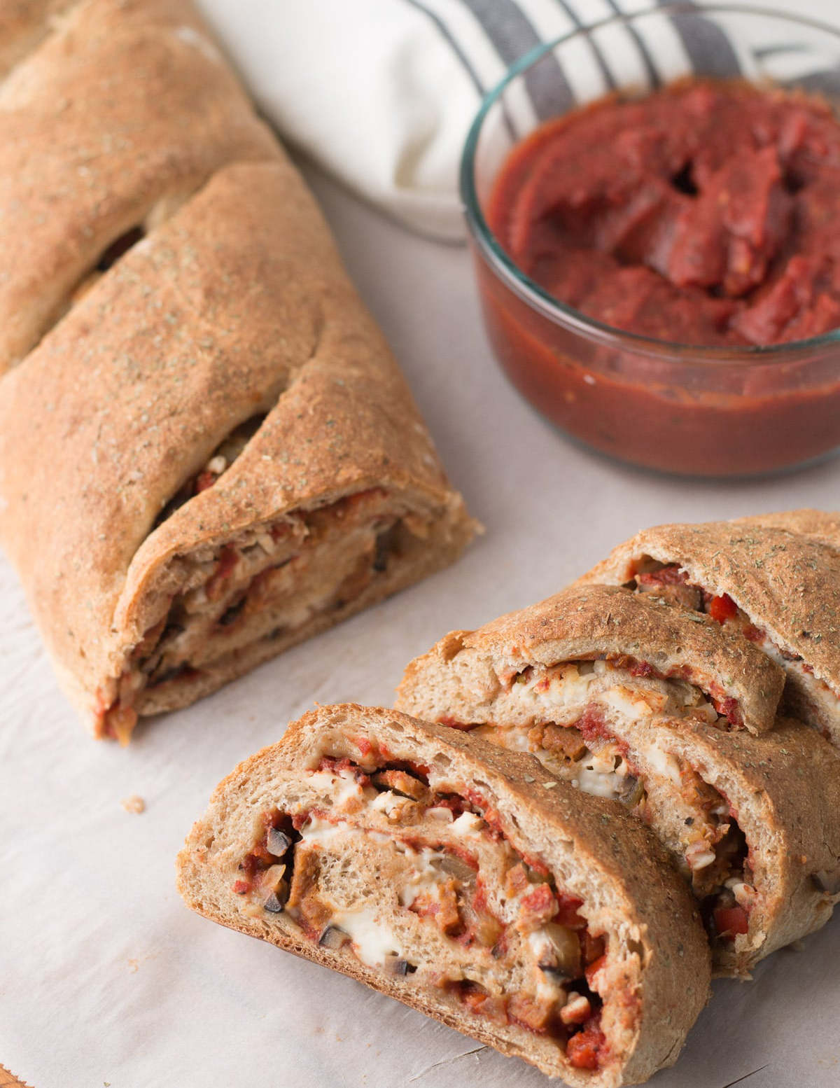 Sliced vegan stromboli served with pizza sauce.