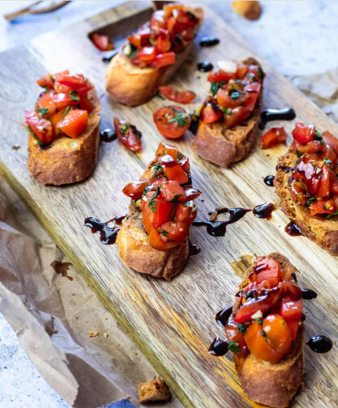 Bruschetta on cutting board drizzle with balsamic glaze.