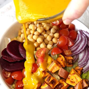 Vegan honey mustard being poured onto a salad.