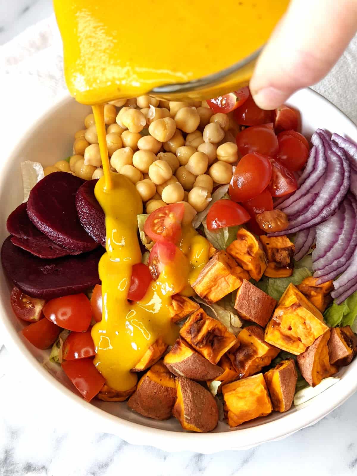 Vegan honey mustard being poured onto a salad.