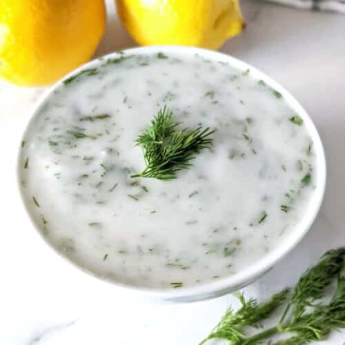 Vegan tartar sauce in a small bowl topped with fresh dill.