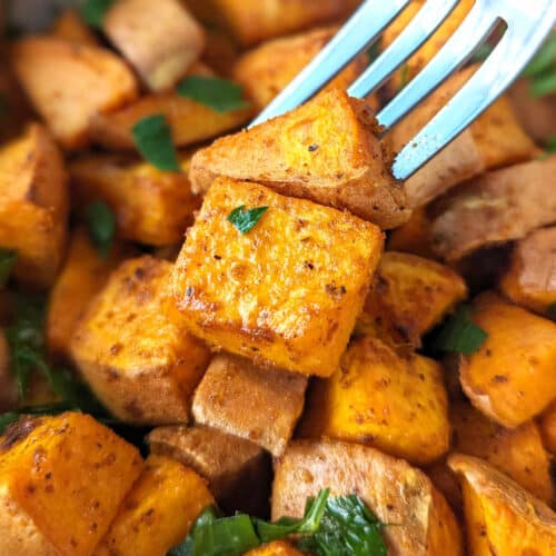 Air fried sweet potato cubes in a bowl with a fork picking up a couple pieces.